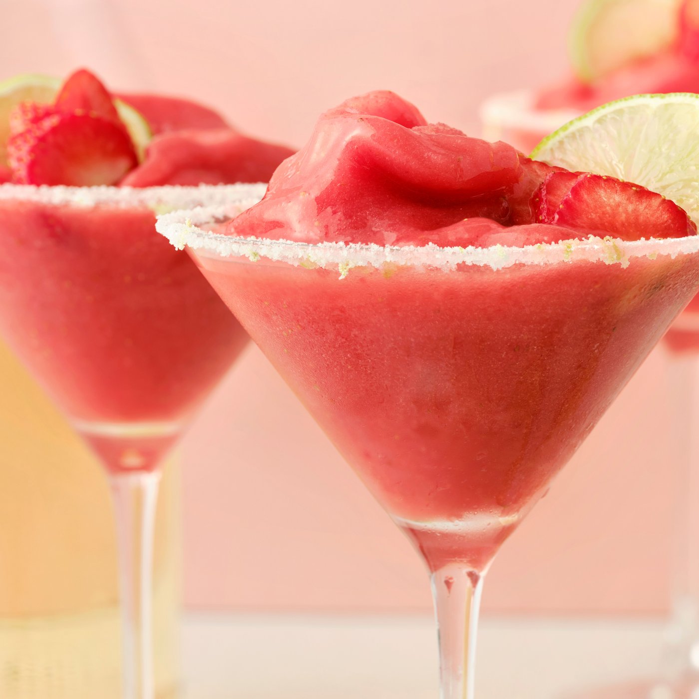 To høje glas fyldt med margaritas af ISKUB læskedrik med hyldeblomst og frosne jordbær, pyntet med lime.