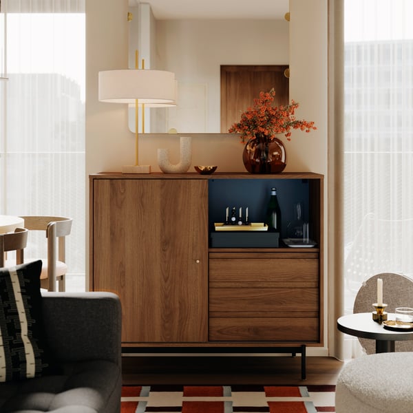 Une lampe de table STOCKHOLM 2025 et un vase avec des fleurs sont posés sur une armoire RÅDMANSJÖ dans un séjour tout droit sorti d’Instagram.