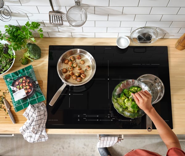 MATMÄSSIG induction hob with pans on it in a kitchen with wooden worktop.