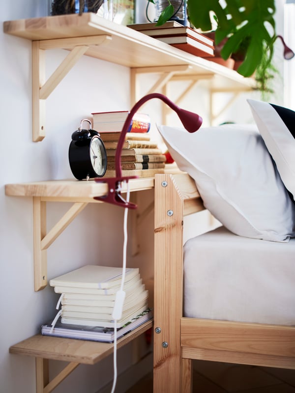 Dark red, NÄVLINGE LED clamp spotlight on an aspen, TRANHULT/SANDSHULT wall shelf at the head of a pine, TARVA bed frame.