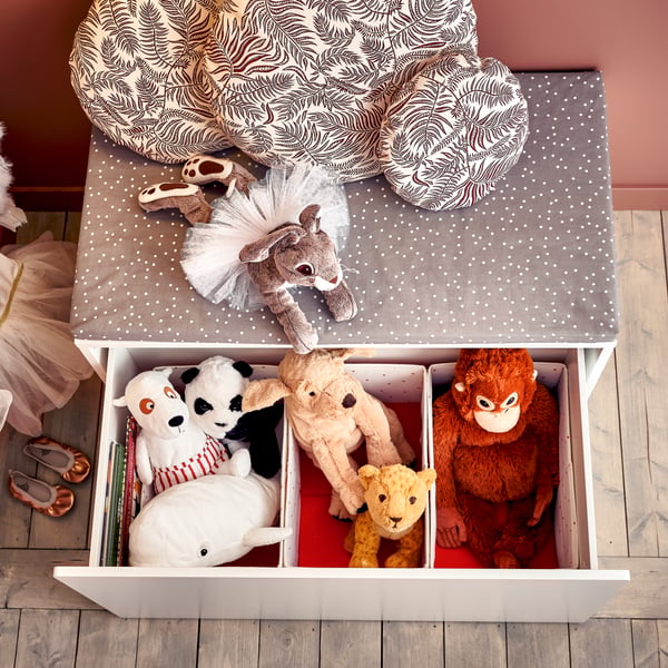 Three NÖJSAM boxes containing soft toys sit inside a SMÅSTAD box which has been pulled out from under a SMÅSTAD bench.