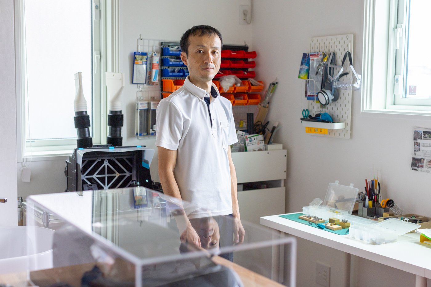 Man standing in his office space, surrounded by well organised tools and items.