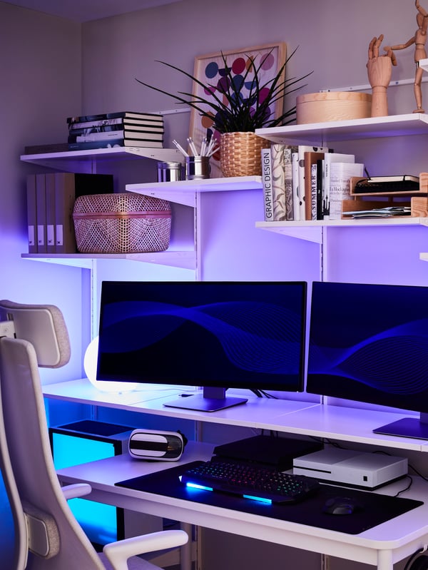 Uno scaffale con due schermi per computer, libri, oggetti decorativi e lampade con luce blu. Accanto c'è una sedia da ufficio.