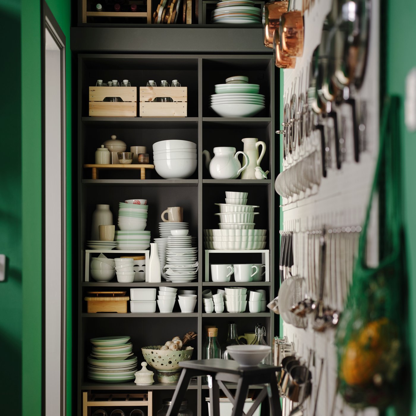 A dark grey VIHALS shelving unit is filled with mainly white dinnerware, but also includes wooden boxes, bottles, and more.