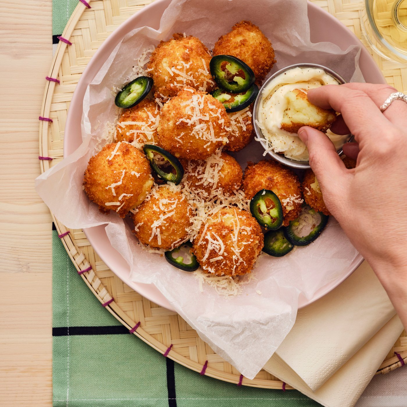 A person’s hand dips a croquette from a serving made from ALLEMANSRÄTTEN mashed potatoes into a creamy sauce.