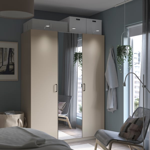 PAX wardrobe with FORSAND and ÅHEIM doors. The doors are beige and mirrored. Additional storage in boxes on top of the wardrobe.