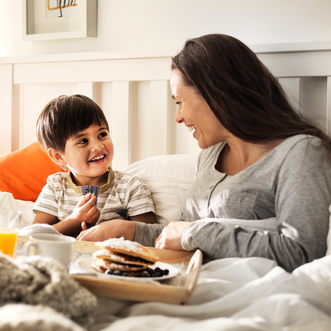 A mother eating breakfast in bed with her child