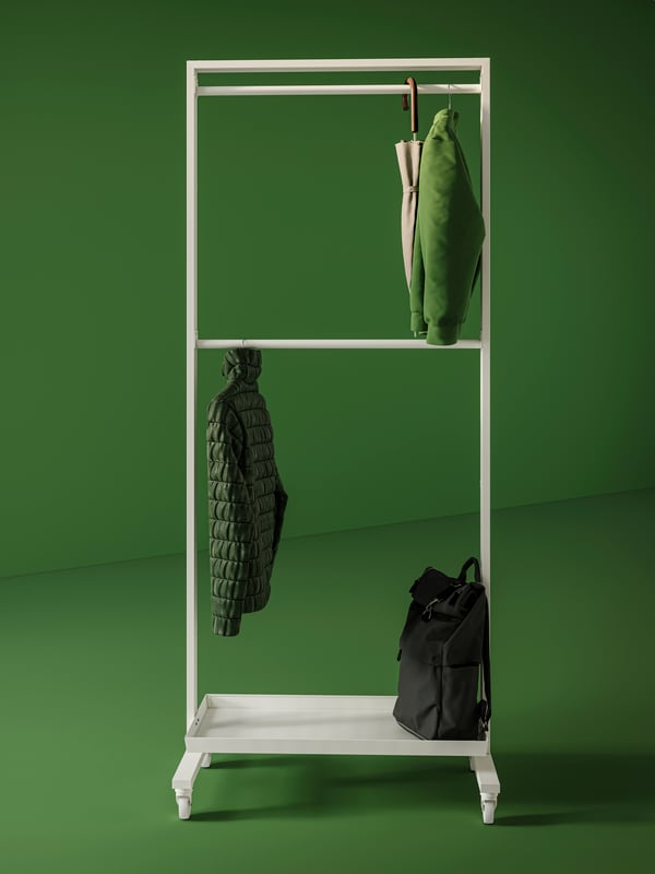 A white MITTZON frame with castors with two jackets and an umbrella hanging from the rails. A bag is placed on the shelf.