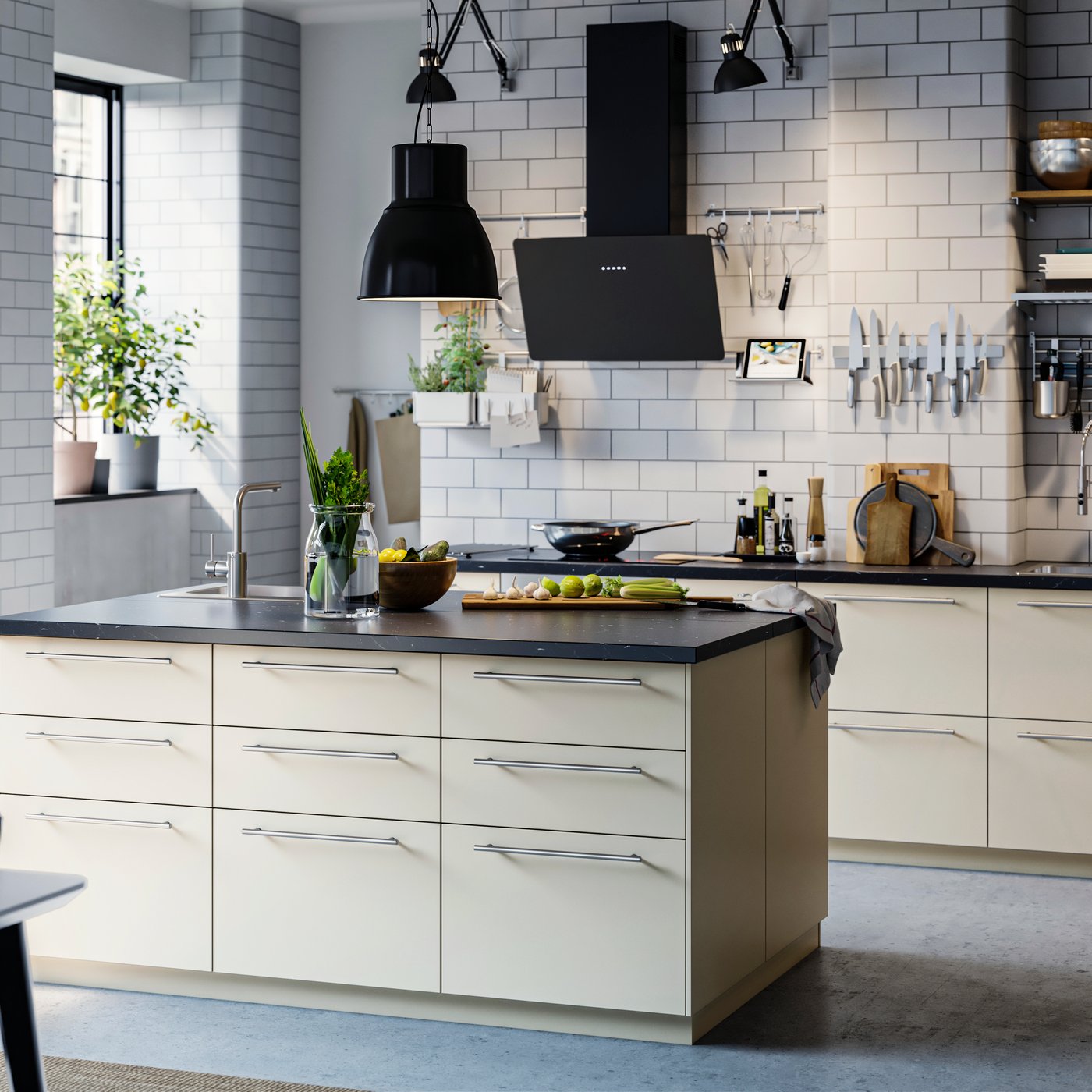 A modern IKEA HAVSTORP matt beige kitchen with an island, dark worktop, black appliances and steel handles.
