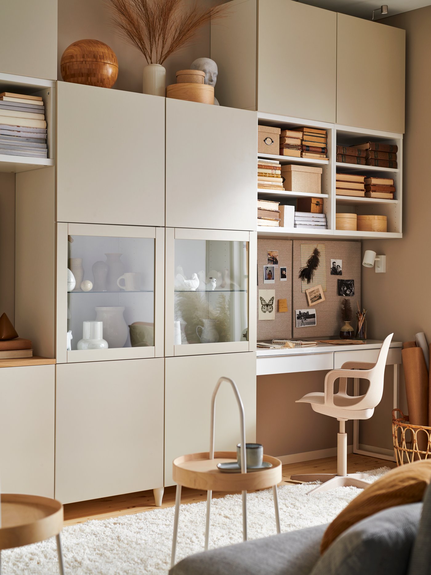 A living room with a BESTÅ storage combination with glass doors with light grey-beige clear glass, and a workstation.