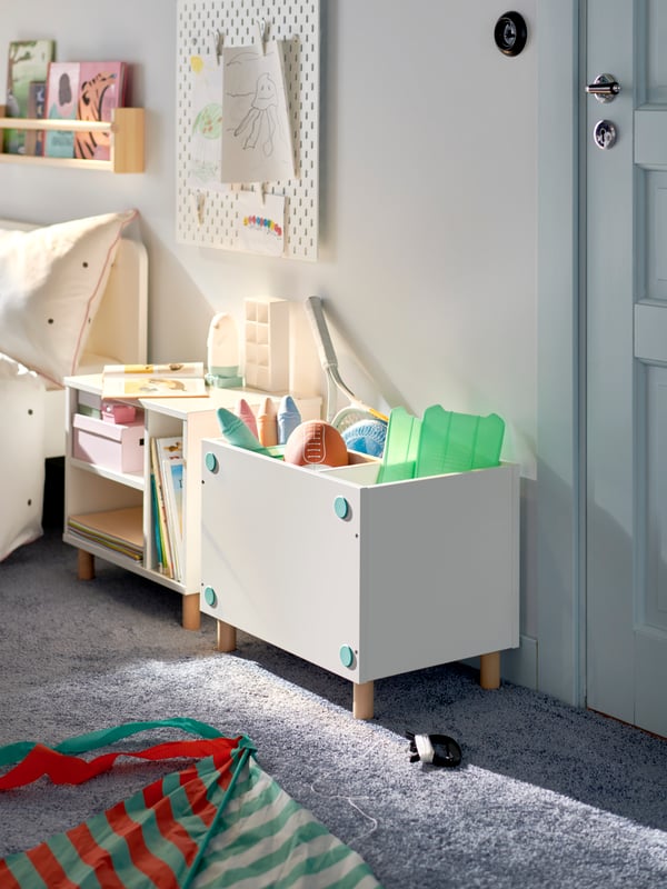 Un dormitorio infantil con un estante SMUSSLA al costado del velador con juguetes en el interior.