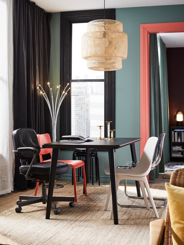 Una mesa de comedor LISABO negra con 4 sillas de diferentes colores y materiales.