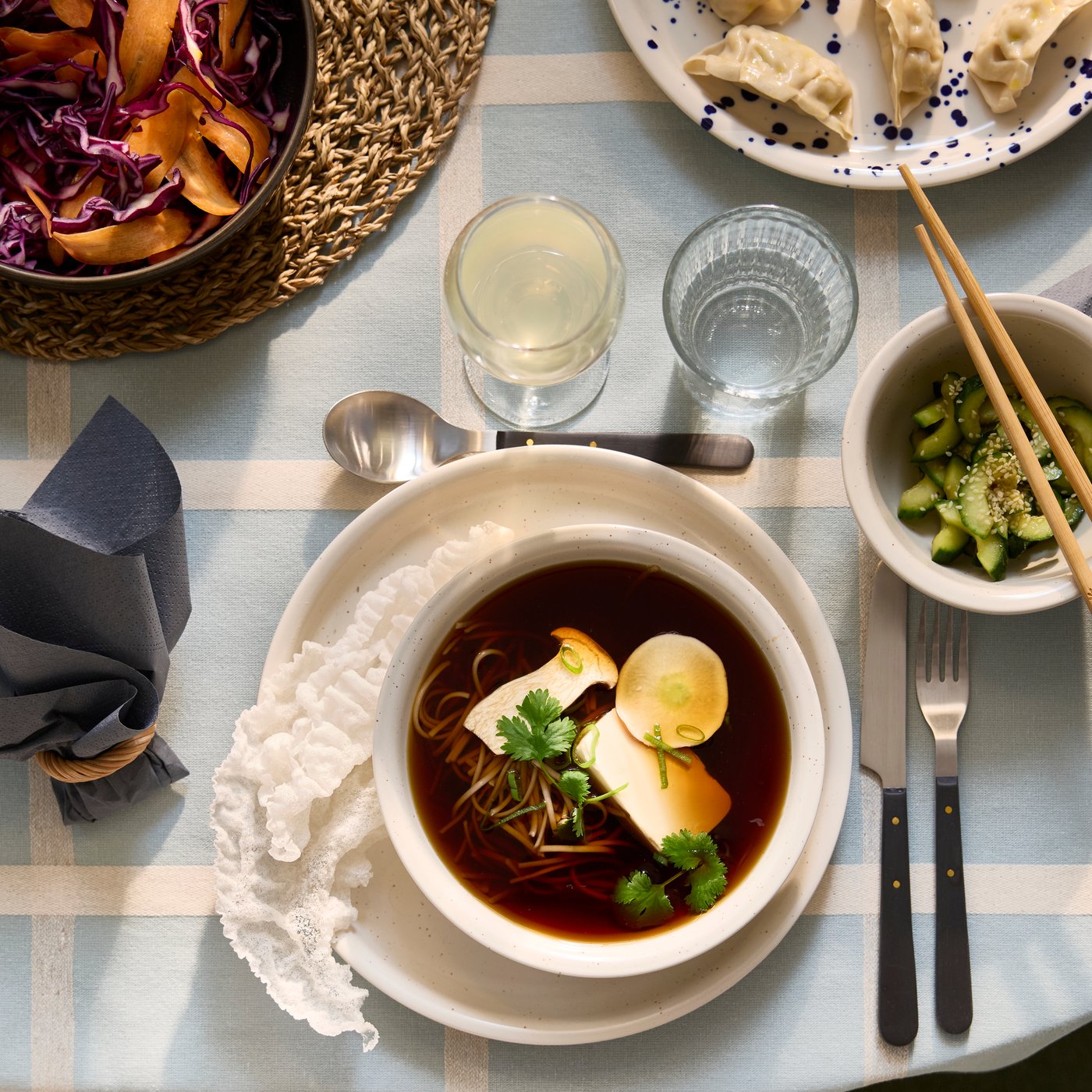 Assiette et bol DAGGASTER tachetés/beiges. Dans le bol, soupe à base de champignons, tofu et nouilles, à côté d’un bol d’avocats.