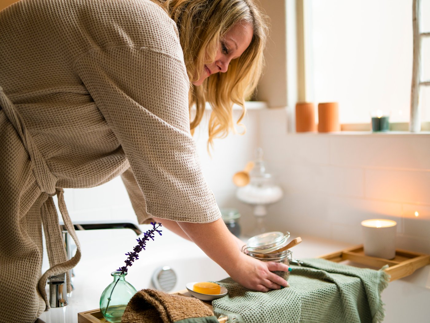 Woman preparing a homemade scrub mix in the kitchen, mixing PÅTÅR press coffee and honey in a KORKEN jar.