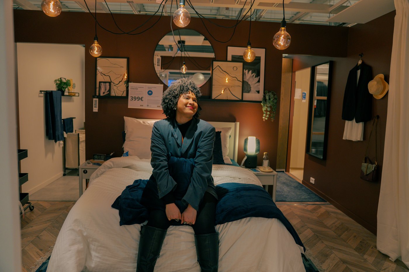 Shadia assise sur un lit dans le showroom d’un magasin IKEA.