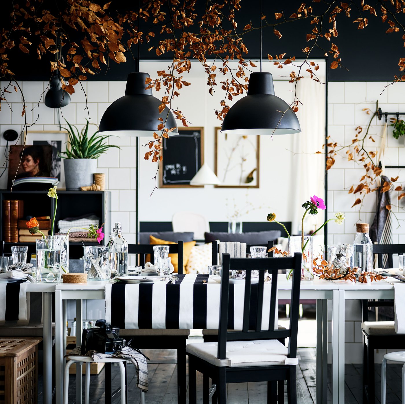 A decked-out black-and-white dining area with brown-black STEFAN chairs and MARIUS stools round two white MELLTORP tables.