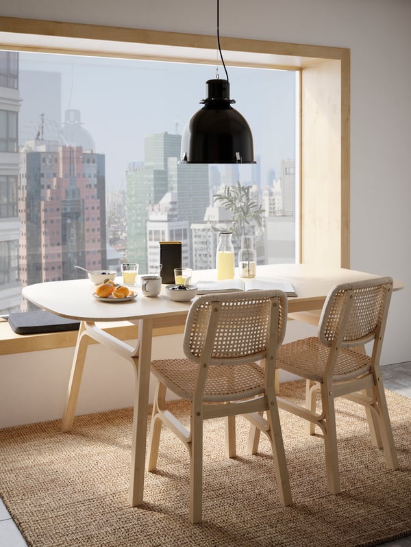 Un comedor frente a un ventanal con vista a la ciudad con dos sillas VOXLÖV.
