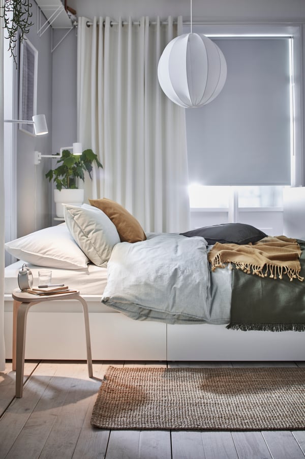 Ein helles Schlafzimmer mit großem Kleiderschrank hinter und über dem Bett