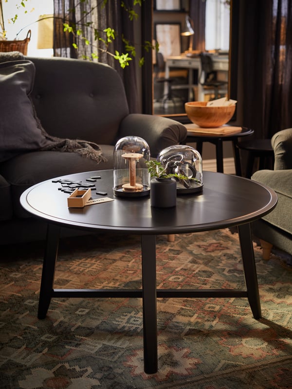 A KRAGSTA coffee table in a dark and atmospheric traditional-style living room with decorative items on top.