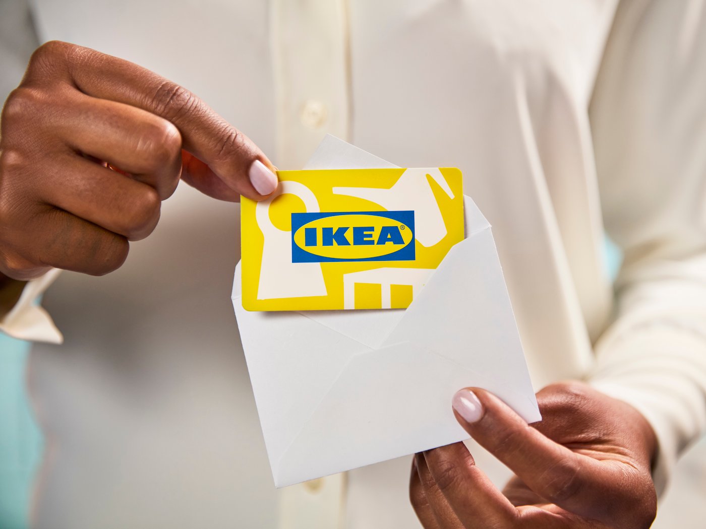 Someone is holding a yellow IKEA gift card with a small white enveloppe.