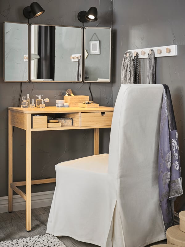 A make-up corner with a NORDKISA dressing table and a HENRIKSDAL chair underneath a wall mirror and two wall lamps.