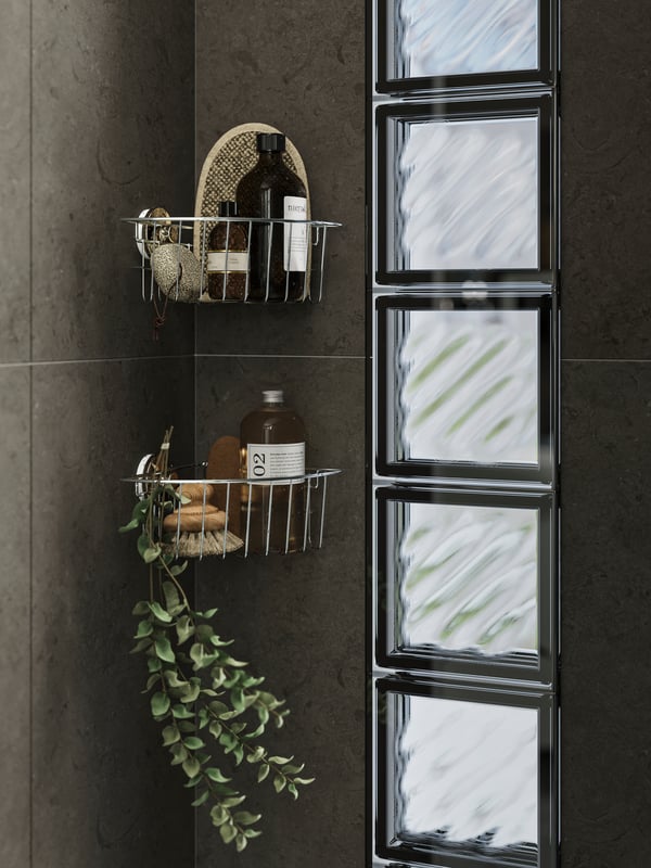 Two KROKFJORDEN corner shelves with suction cups on the wall in a brown shower corner holding toiletries and body care items.