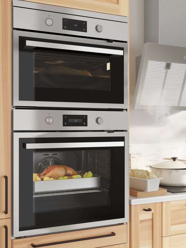 An ANRÄTTA forced-air oven with pyrolytic function in stainless steel by a wall-mounted extractor hood and kitchen items.