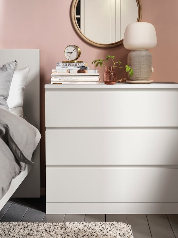 Cómoda blanca MALM de tres cajones junto a cama con respaldo blanco.