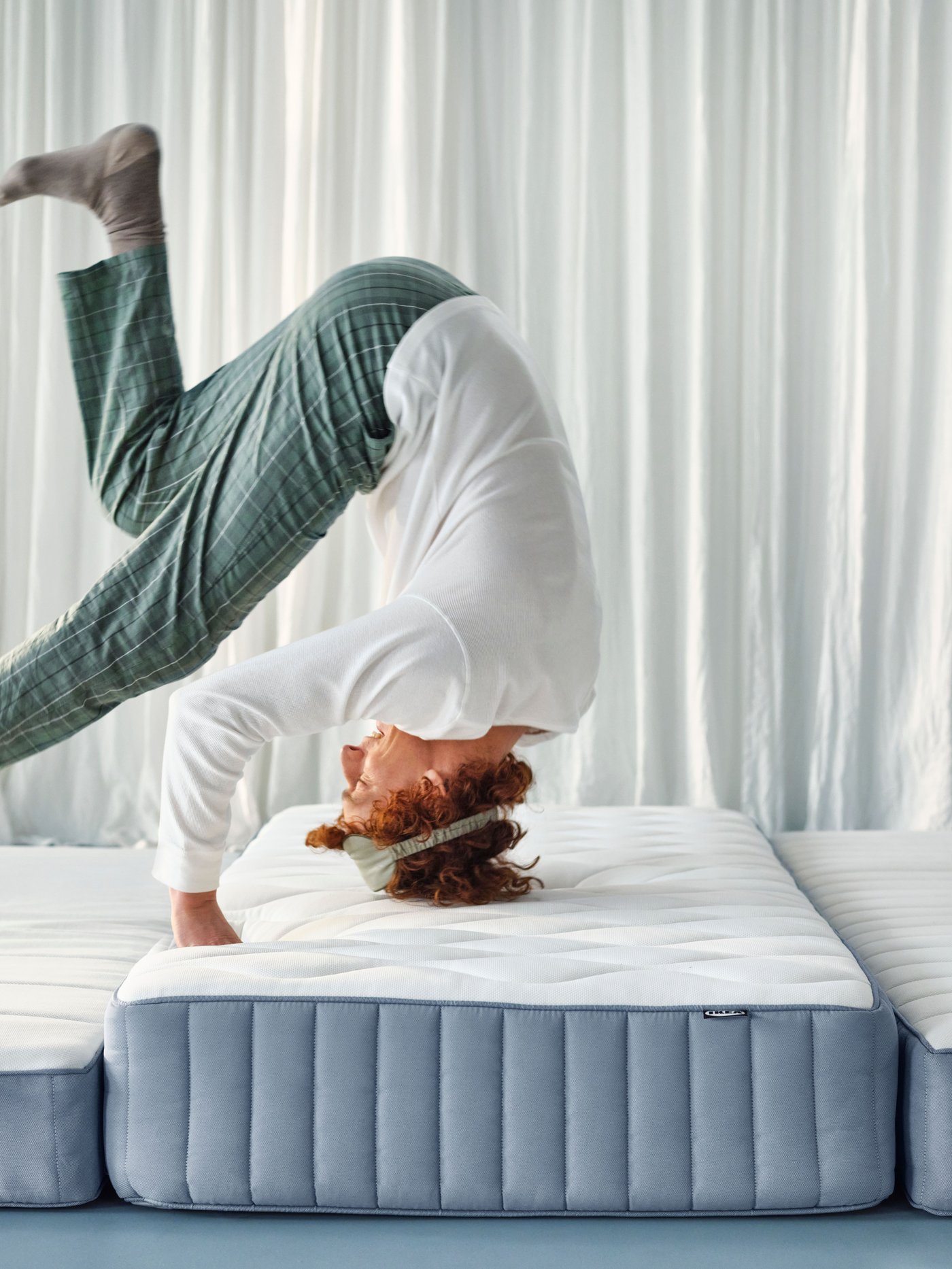 A person in pyjamas is doing a somersault on the VALEVÅG pocket spring mattress