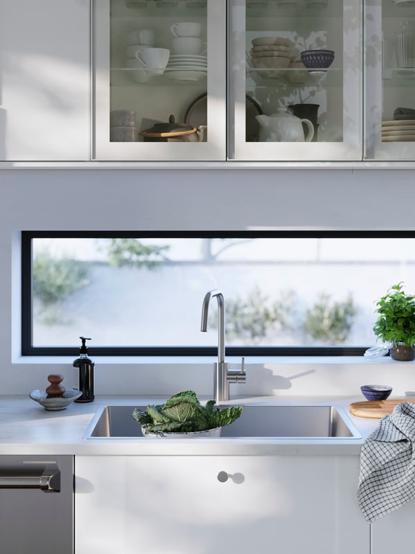 Cabinets with HEJSTA glass door are mounted above a VRESJÖN inset sink and an ÄLMAREN kitchen mixer tap in stainless steel.