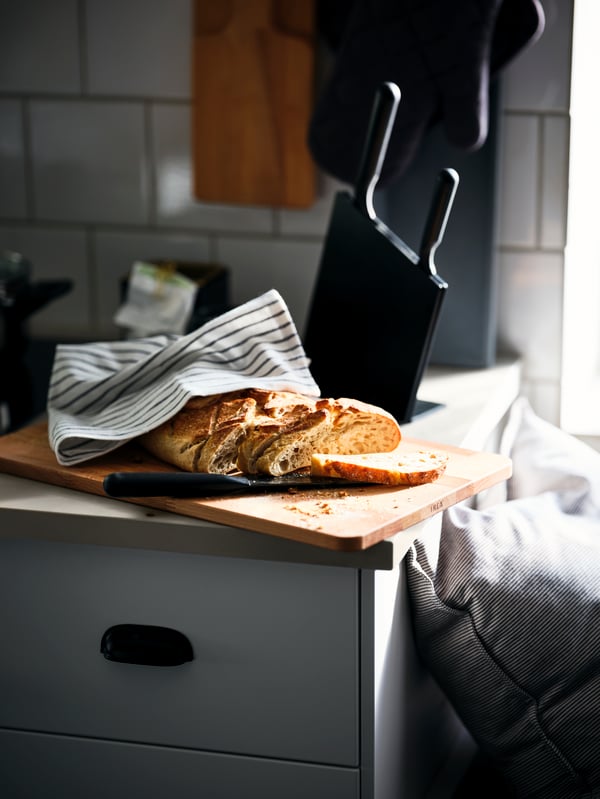Unbaked apple pie, IKEA baking utensils, blue and white tea towels and two knives on a chopping board.