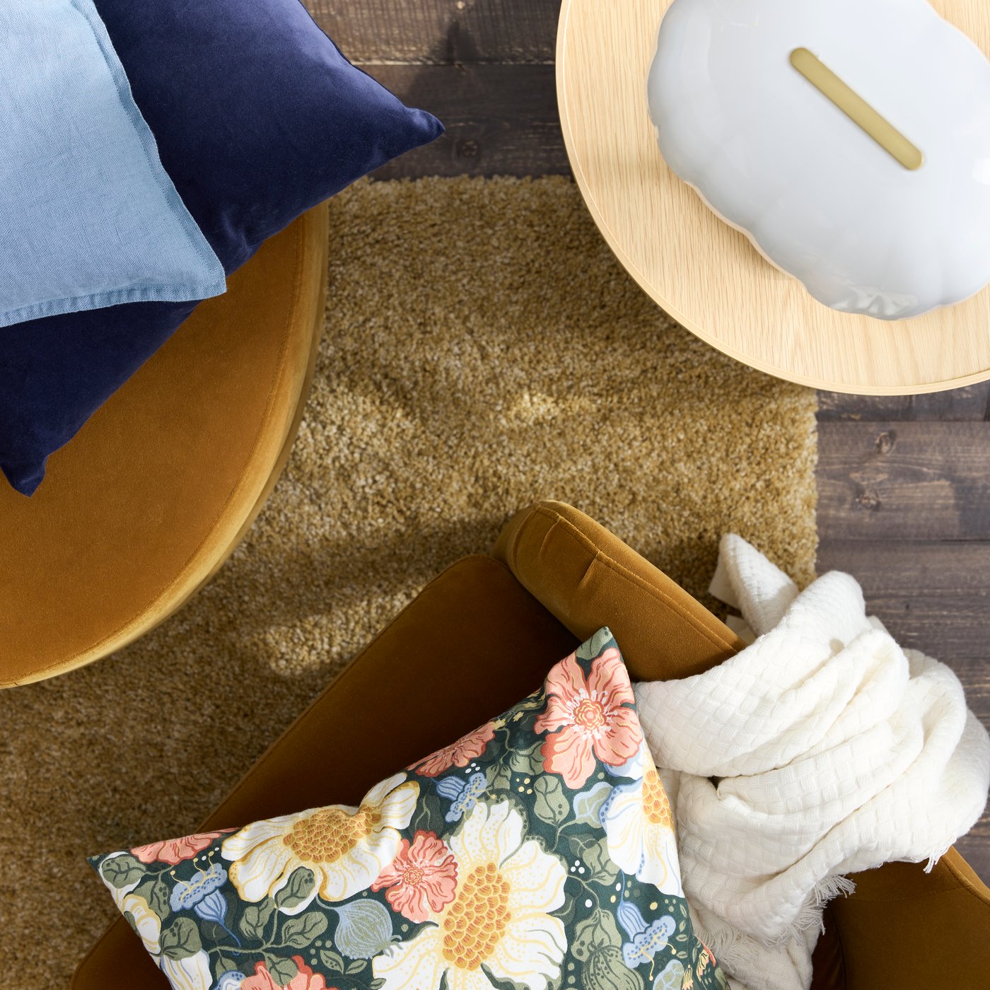A floral-pattern cushion on a dark-yellow-brown FAGERBACKEN armchair standing on a deep-beige BREVBÄRARE high-pile rug.