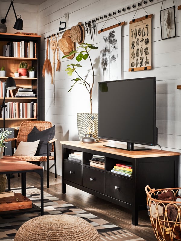 A traditional living room with a TV bench and a bookcase in black-brown/solid pine and decorative items in natural materials.