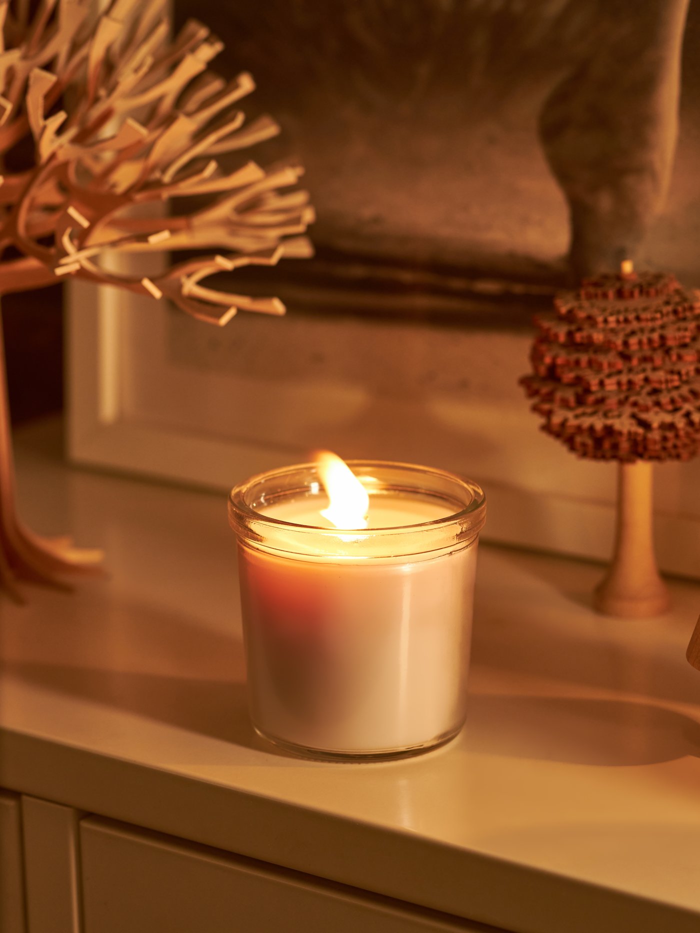 A burning ADLAD scented candle in a glass.