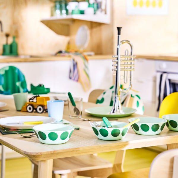 OFTAST bowls with green spot motif on a family dinner table in a Scandinavian modern kitchen.