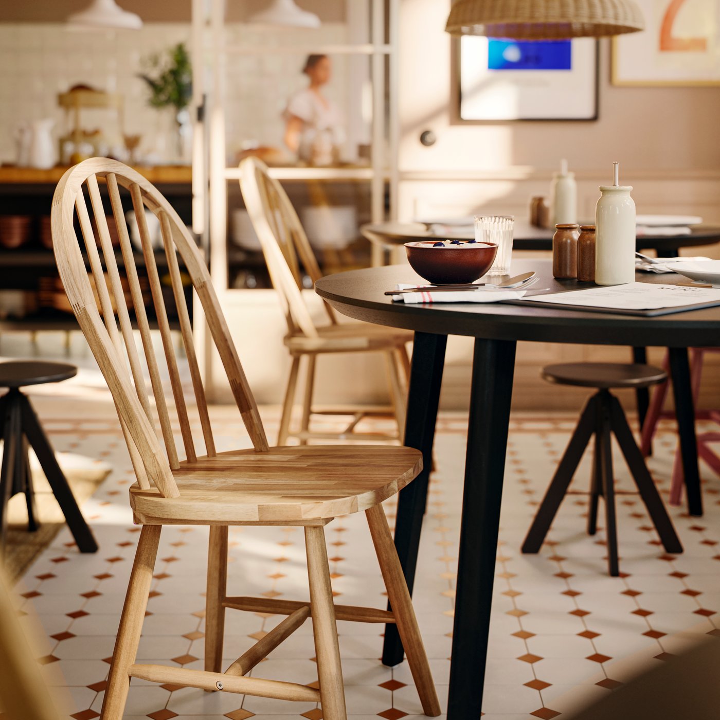 A solid acacia SKOGSTA chair with an arched backrest and spindles is at a dark, round table in a commercial dining area.