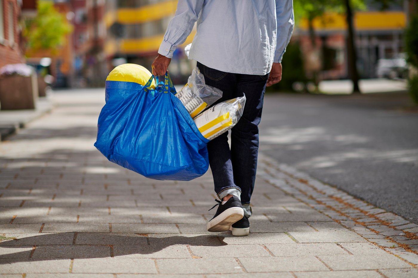 muž který jde z nákupu z ikea s modrou taškou frakta