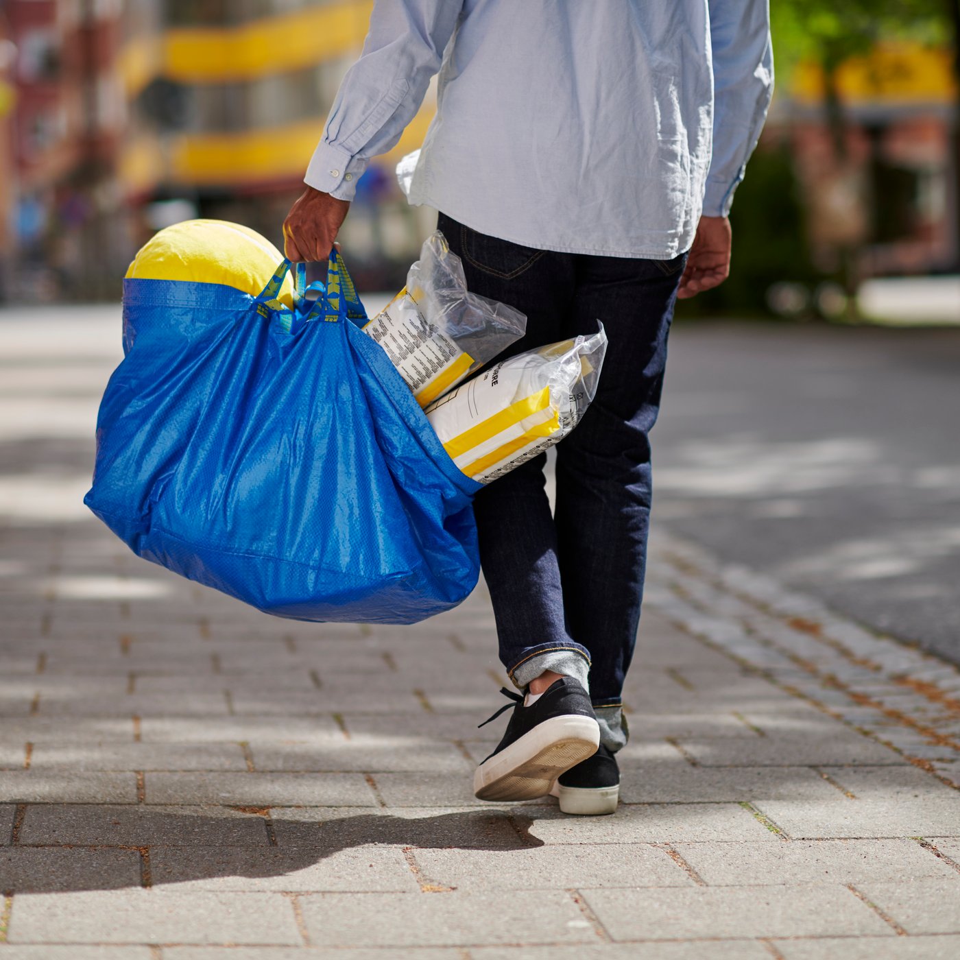 muž který jde z nákupu z ikea s modrou taškou frakta
