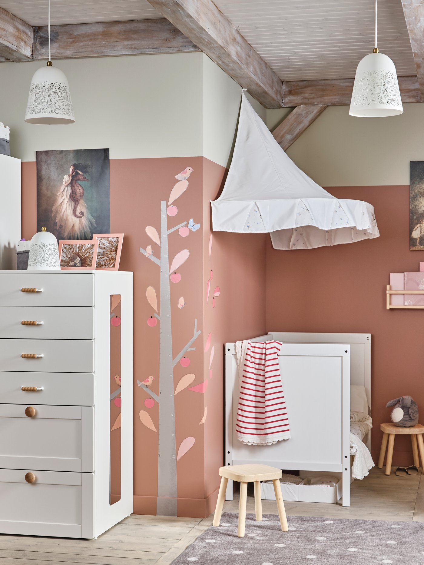 Einrichtungsidee für ein Kinderzimmer in Weiß/Rosa mit einem Kinderkleiderschrank und einem Babybett mit Betthimmel in Weiß im traditionellen Stil und einem roten Schaukelelch.