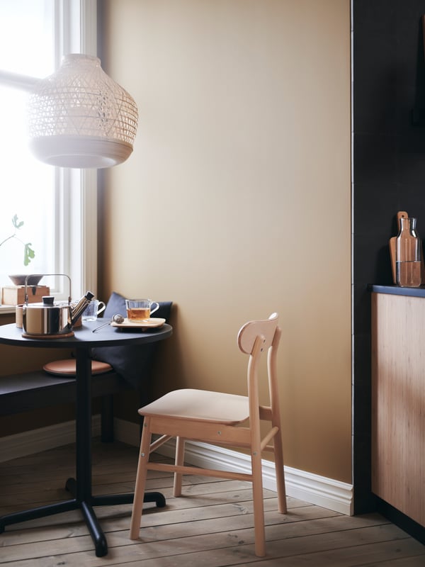 The STENSELE table and RÖNNINGE chair with a hanging lampshade and breakfast on the table make a cosy breakfast corner.