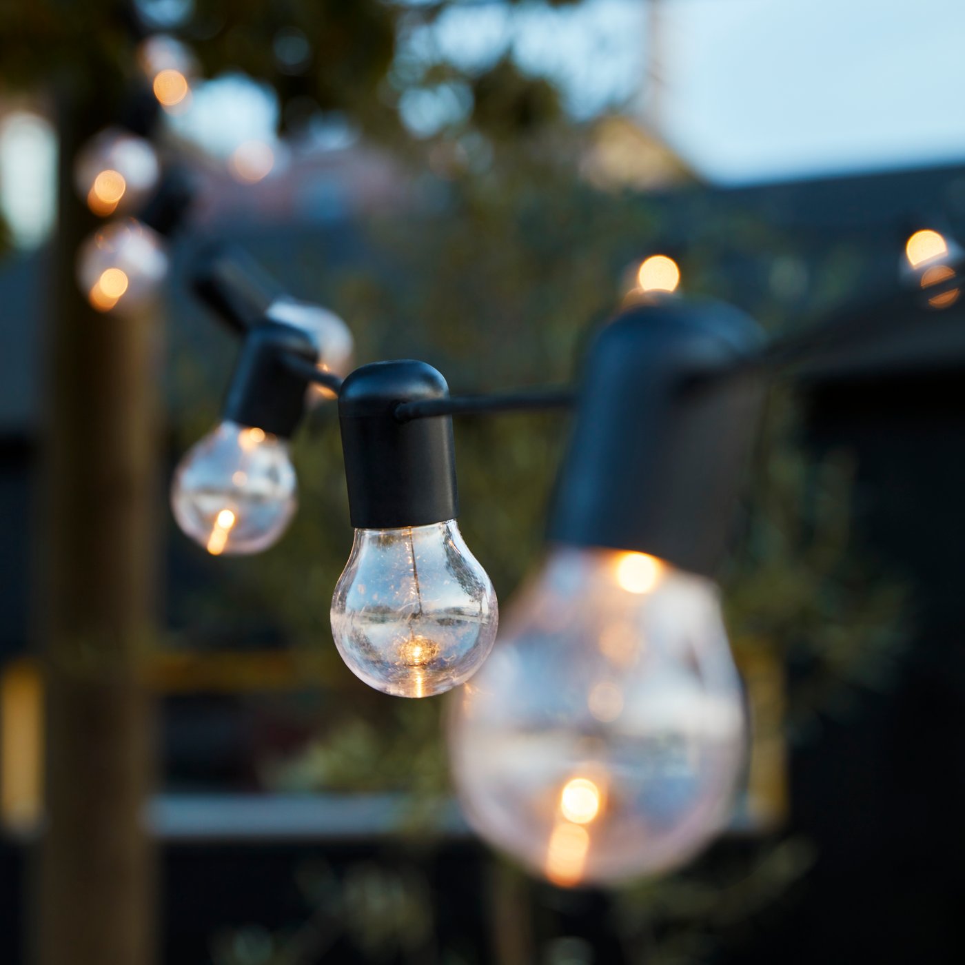 UTSUND outdoor chain lighting in the garden area, hanging from poles.