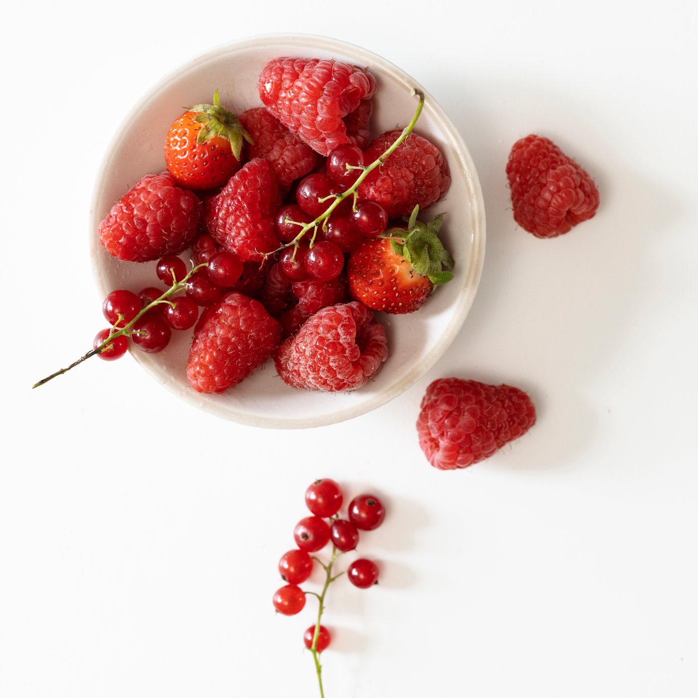 Vela aromática LOTSFÅGEL aroma Frutos rojos en un recipiente de vidrio color rosa claro, en un espacio interior.