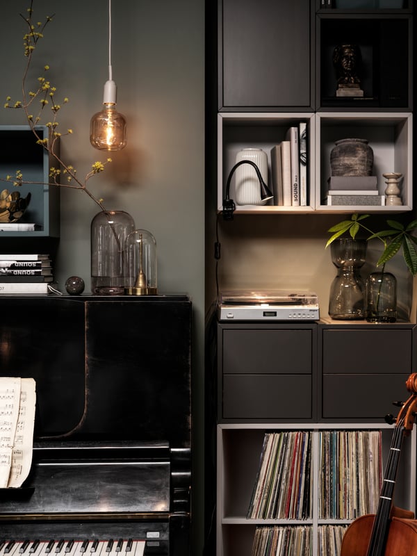 A piano and a vertical arrangement of EKET cabinets stand side by side. Free surfaces are dotted with decorative items.