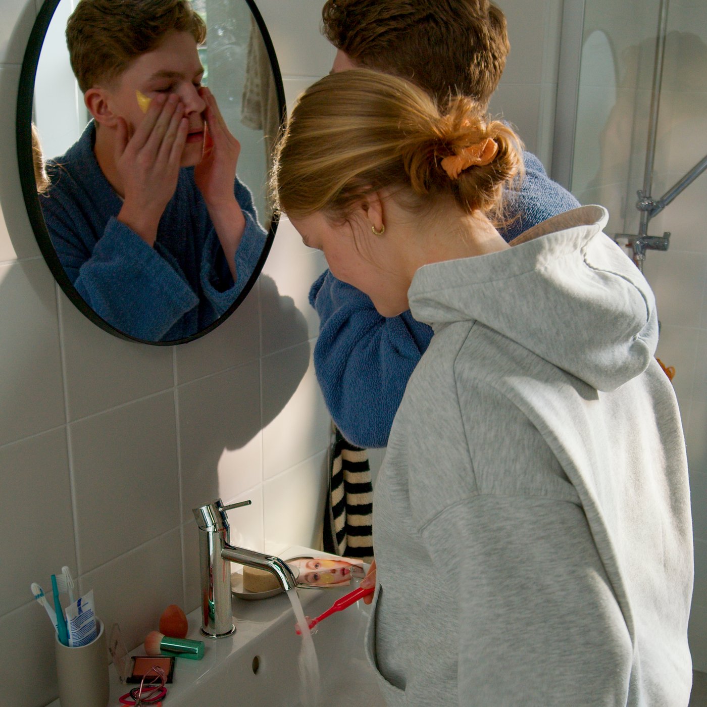Two people in a bathroom sharing a wash-basing with a SALLSJÖN bathroom mixer tap with a top lever.