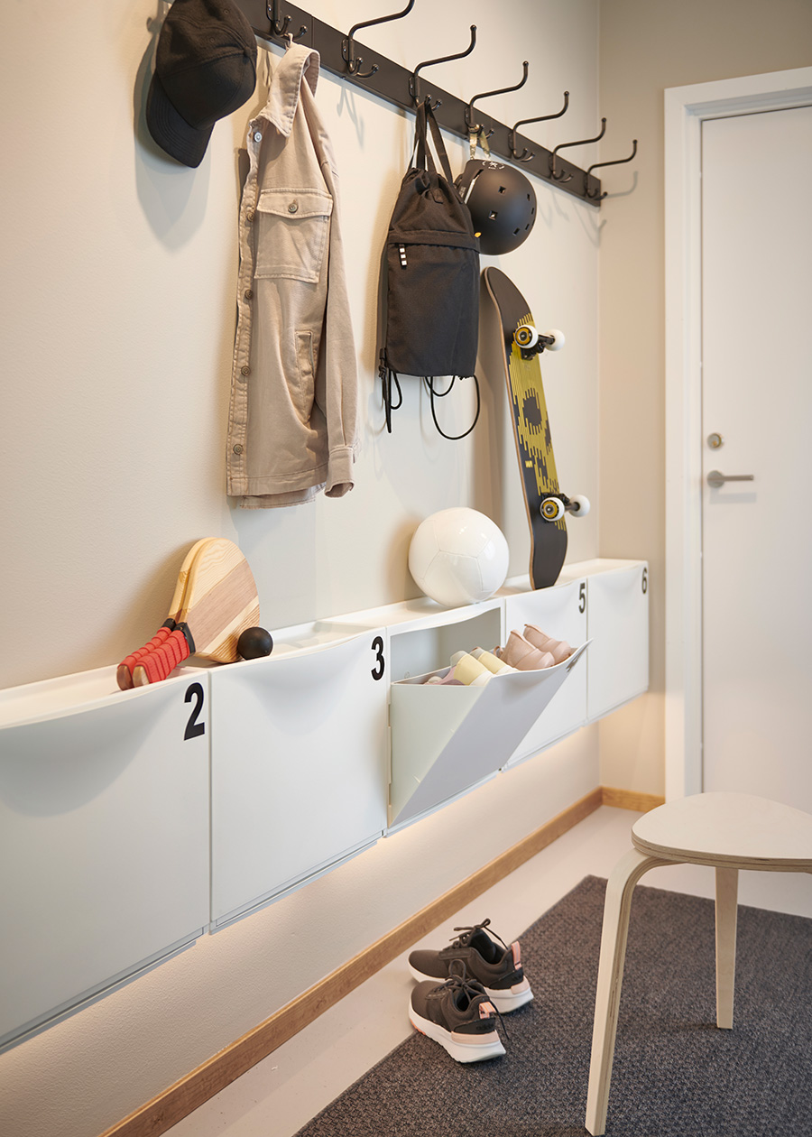 Una entrada de casa con zapateros IKEA y un gancho PINNIG con ropa y gorros.