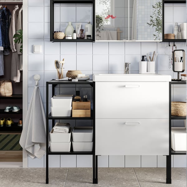 A bathroom has white ENHET base cabinets and ENHET base frames with shelves in anthracite with bathroom items placed on them.