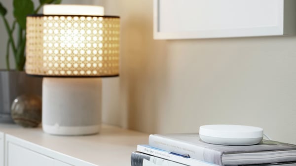 IKEA SYMFONISK lampa na komodi pored DIRIGERA baze.