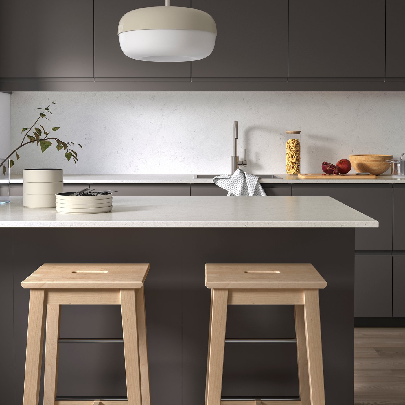 A kitchen with LOCKEBO custom-made worktop in white/grey on the kitchen island, tableware, and two wooden kitchen stools.