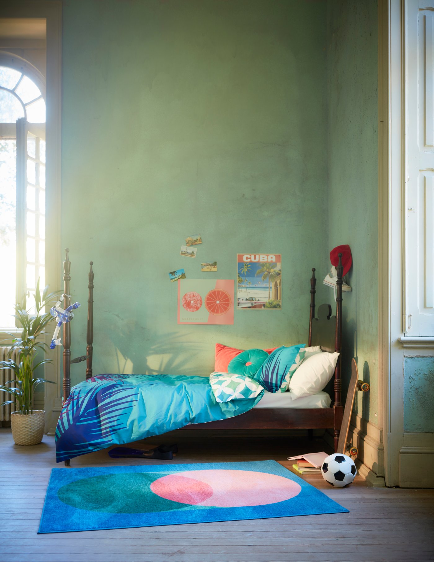 Ein Scandi-boho Schlafzimmer für Kinder mit Textilien in Blautönen und einem bunten Teppich mit Spielzeug auf dem Boden.