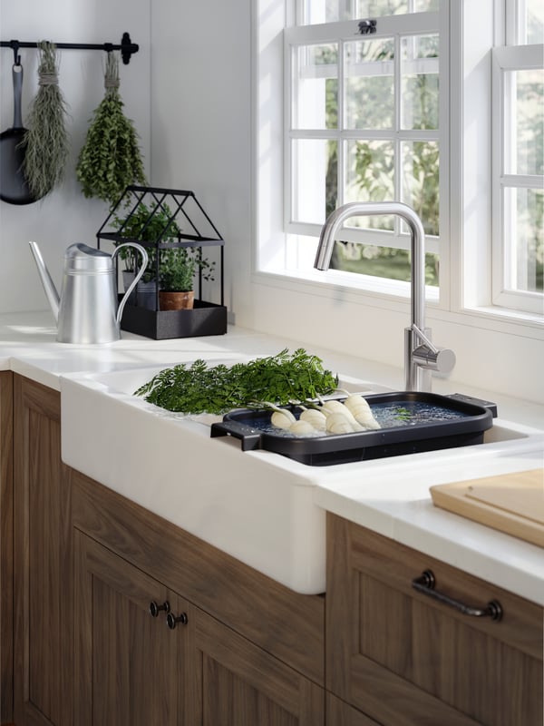 A white HAVSEN sink in a traditional style kitchen with an ÄLMAREN mixer tap and sink in anthracite with vegetables.